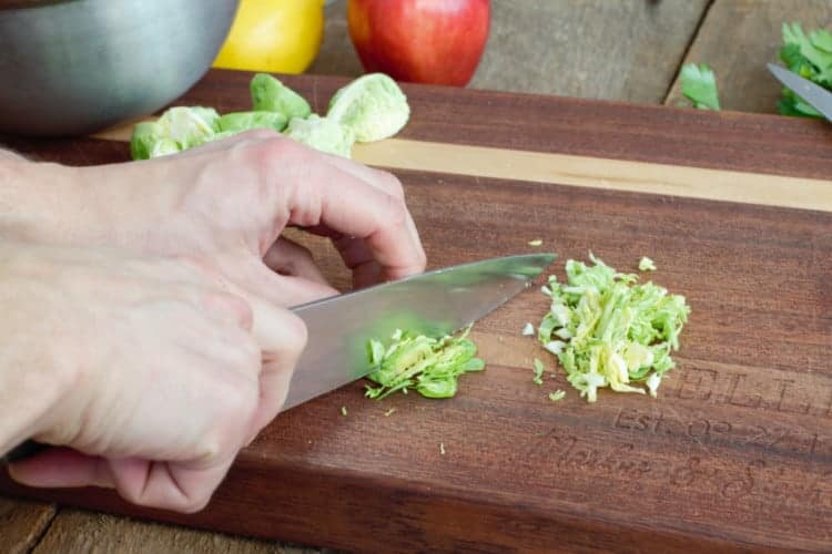 thinly shaving the trimmed brussels sprouts with a chefs knife