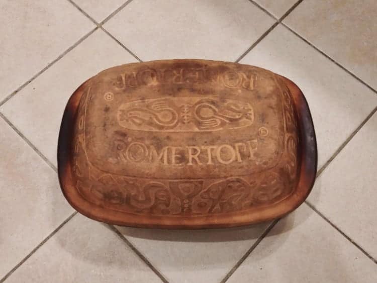 overhead shot of a used romertopf lid on a white tile background