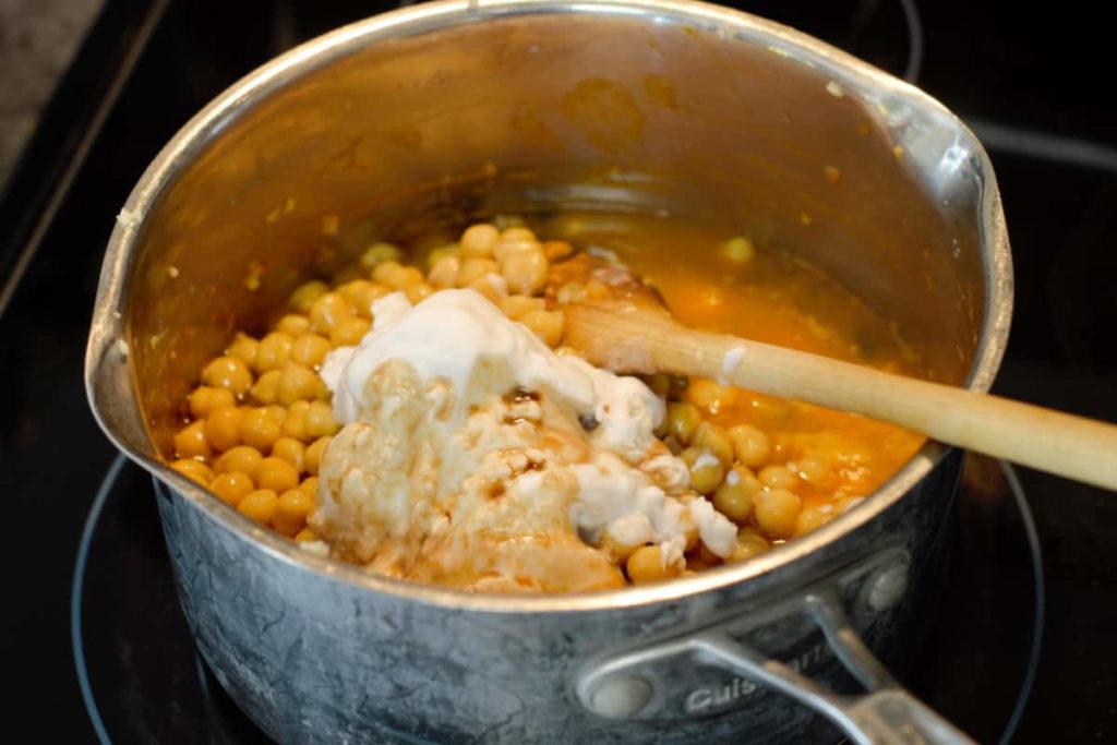 adding coconut milk, chickpeas, and soy sauce to the curry as it cooks