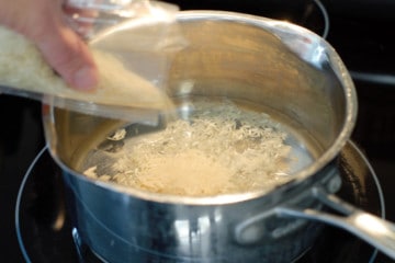 adding raw basmati rice to a pot of water