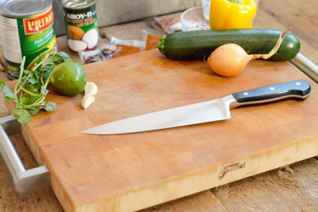 ingredients needed to make spiced chickpea curry on a wooden cutting board