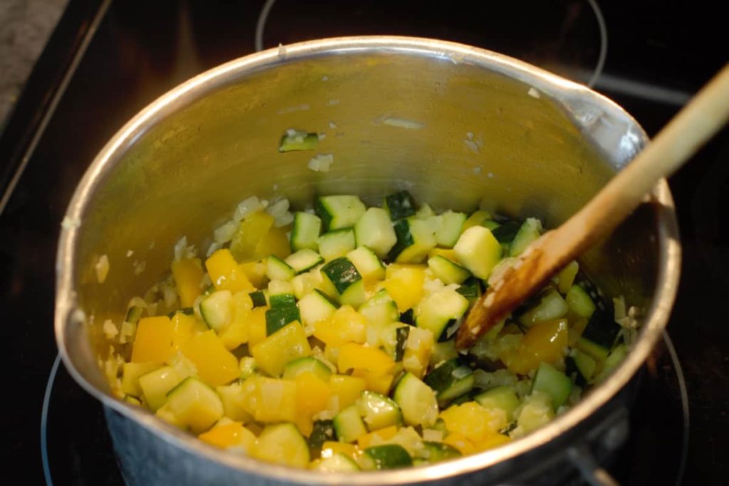 chopped onions, zucchini, bell pepper, and garlic turning translucent as it cooks