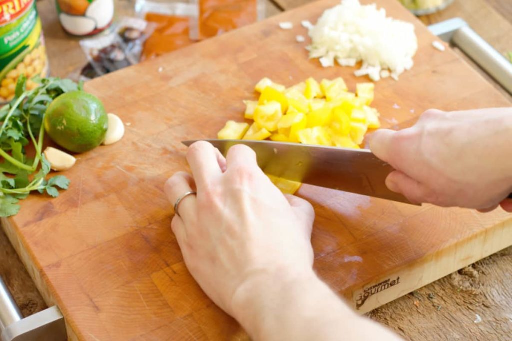 chopping yellow bell pepper on a wooden cutting board