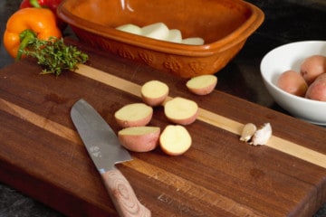 cutting vegetables on a wooden cutting board surrounded by various items