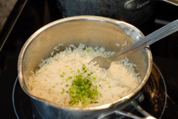 seasoning the cooked basmati rice with chopped cilantro stems and lime zest