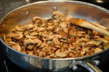 adding mushrooms to the pan of bacon and onions