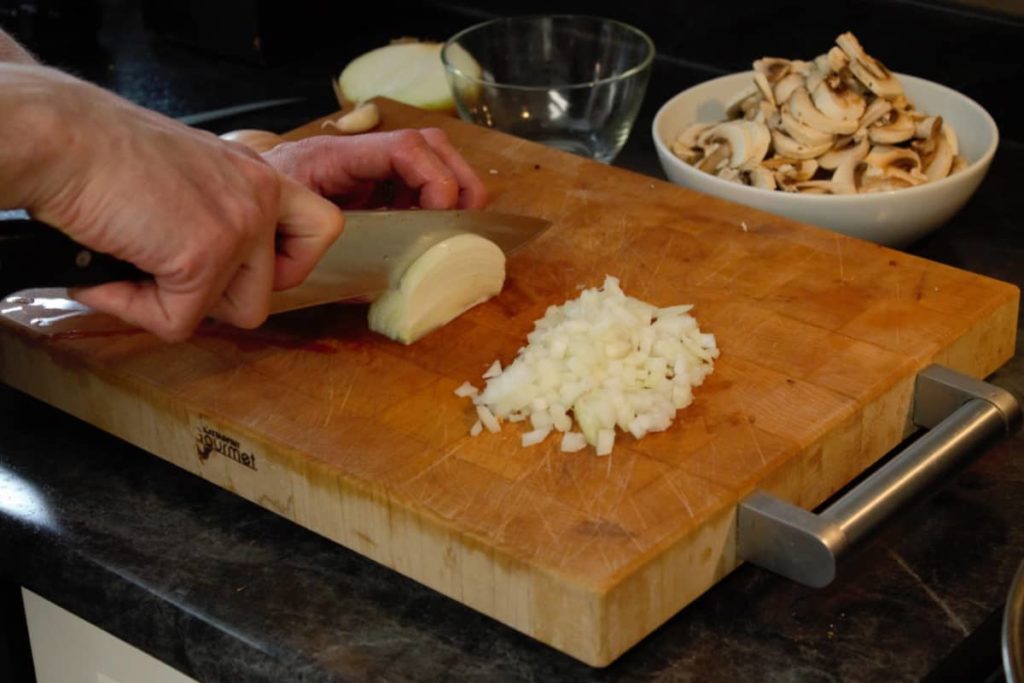 dicing spanish onion on a wooden cutting board