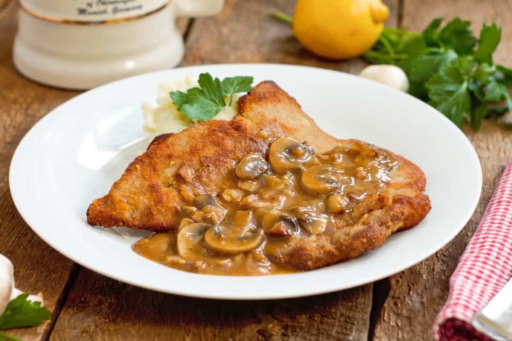 jJägerschnitzel served with mashed potatoes and parsely on a barnboard tabletop