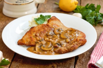 jägerschnitzel served with mashed potatoes and parsely on a barnboard tabletop