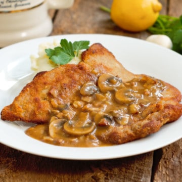 jägerschnitzel served with mashed potatoes and parsely on a barnboard tabletop