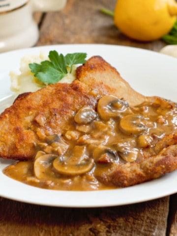 jägerschnitzel served with mashed potatoes and parsely on a barnboard tabletop