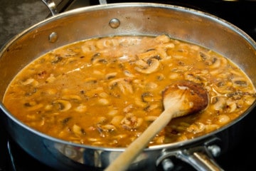 adding beef broth and wine to the pan of Jägerschnitzel sauce