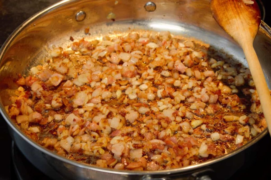 browned bacon bits and translucent onions in a pan while cooking