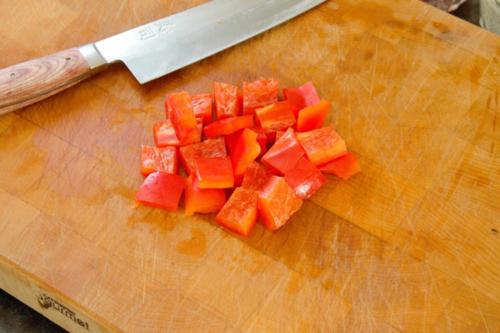 close up of diced red bell pepper on a wooden cutting board