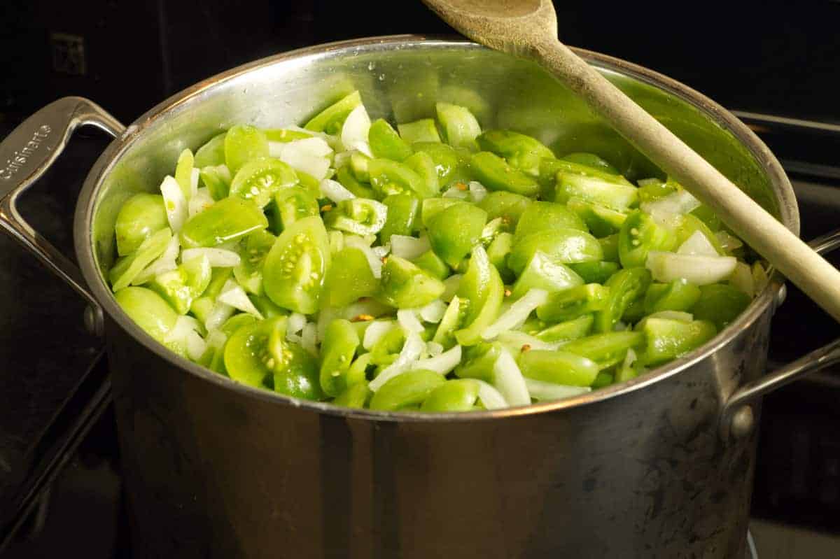 Green tomato chow mixture just starting to cook on the stove in a steel pot