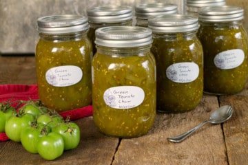 canadian green tomato chow chow in labeled mason jars on a rustic wooden surface