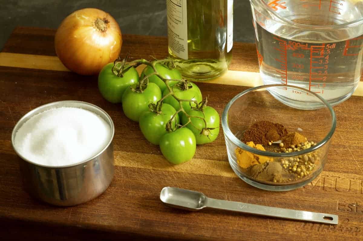 some of the ingredients needed to make green tomato chow displayed on a wooden cutting board