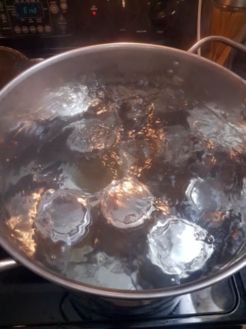 mason jars processing in a large pot of boiling water