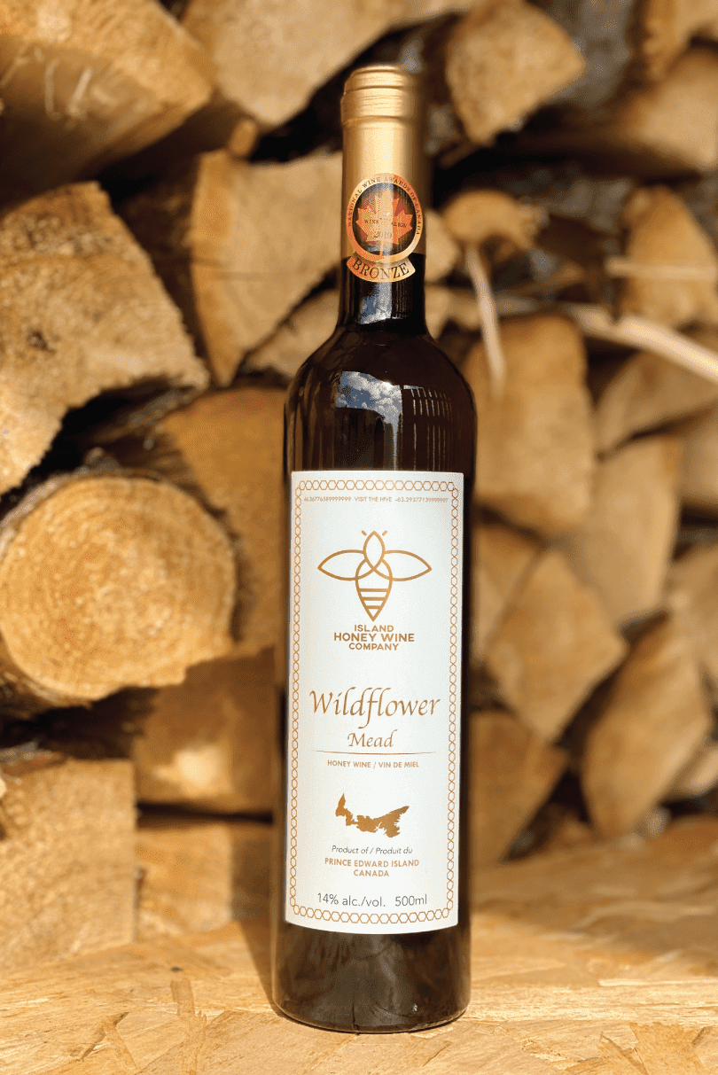 a bottle of wildflower mead in front of a dried firewood log backdrop