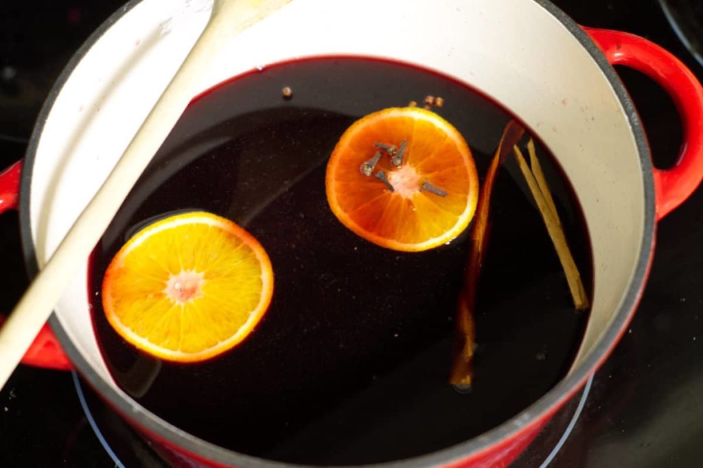 gluhwein mulling in an enameled pot with orange slices, cinnamon and cloves.