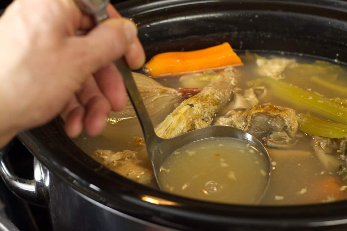using a ladle to scoop out finished turkey stock