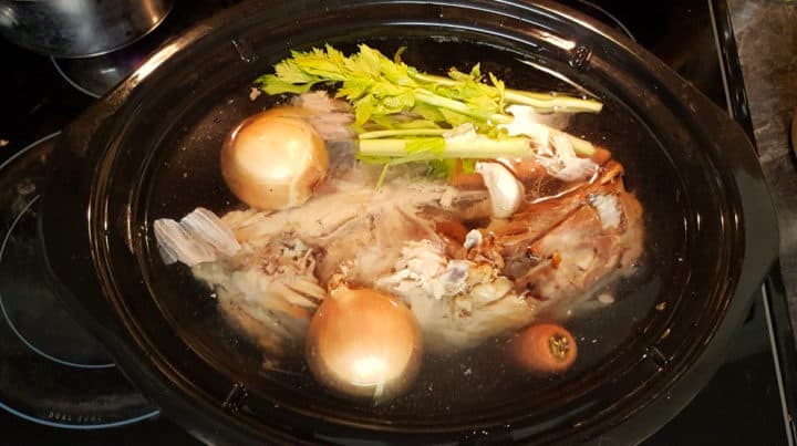 top down image of the slowcooker before the turkley stock has been cooked.