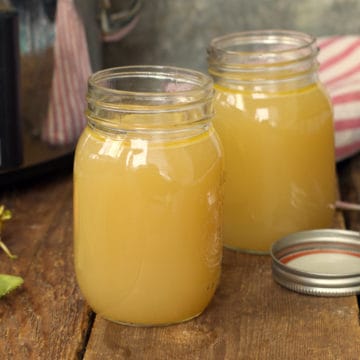 slow cooker turkey stock in glass mason jars on a rustic wood backdrop