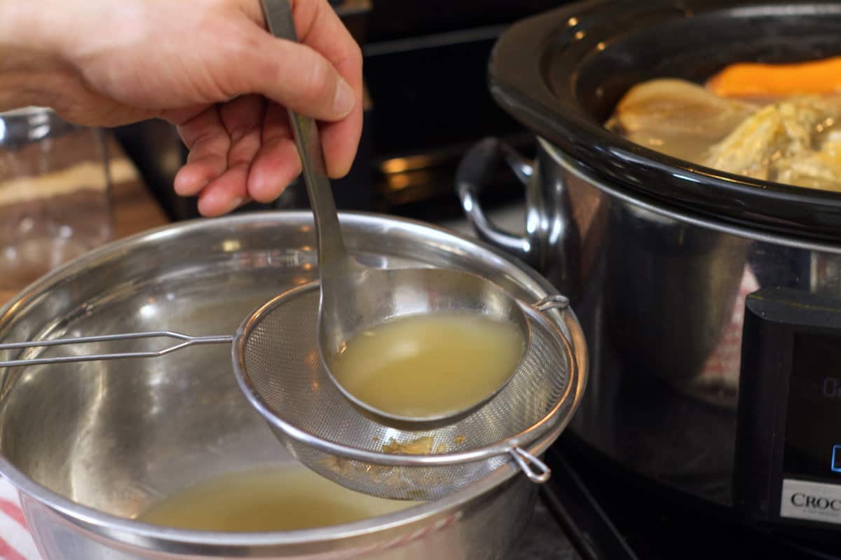 straining the turkey stock through a mesh strainer