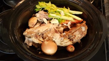 overhead image of all turkey stock ingredients in a slow cooker