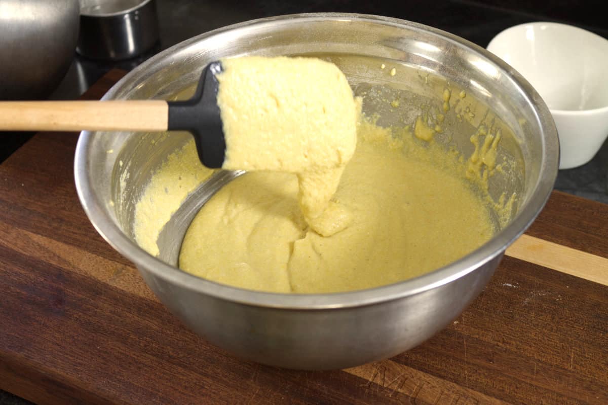 showing the correct consistency of the cornbread batter with a black spatula