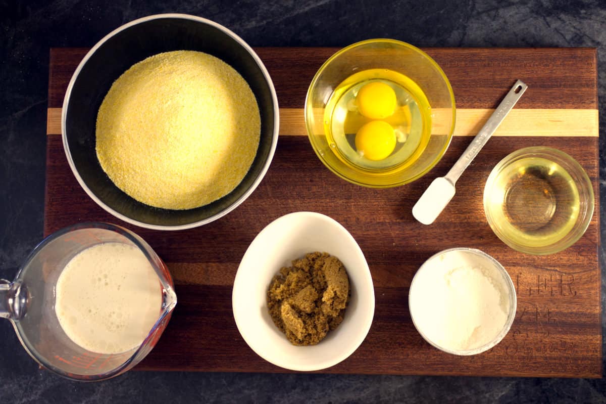 various ingredients needed to make dairy free cornbread in bowls on a wooden cutting board