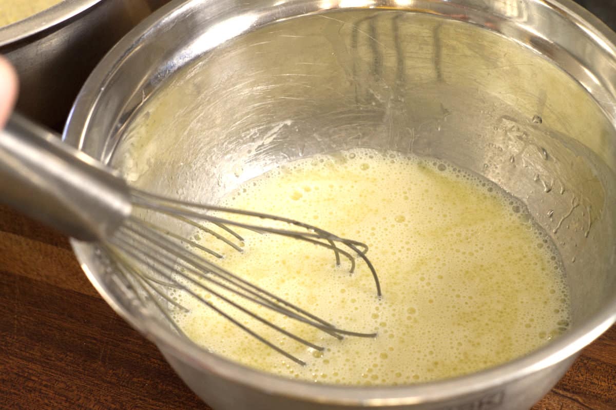 mixing the wet cornbread ingredients with a whisk in a metal bowl