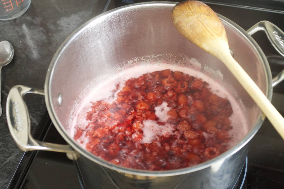 raspberries simmering in a stainless steel pot on the stove