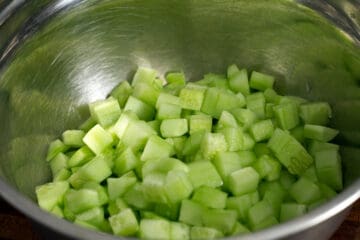 peeled and cubed cucumber in a stainless steel bowl.