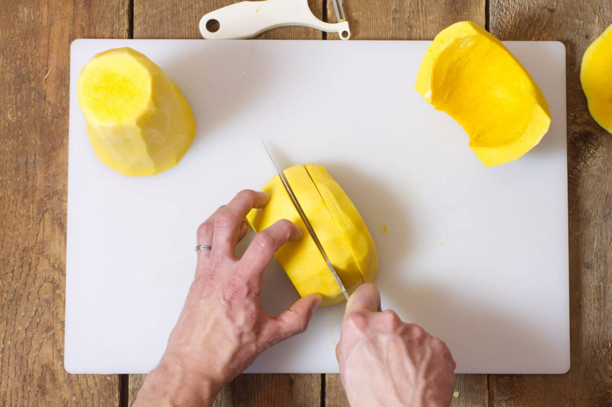 Top down view of a butternut squash being cut into strips.