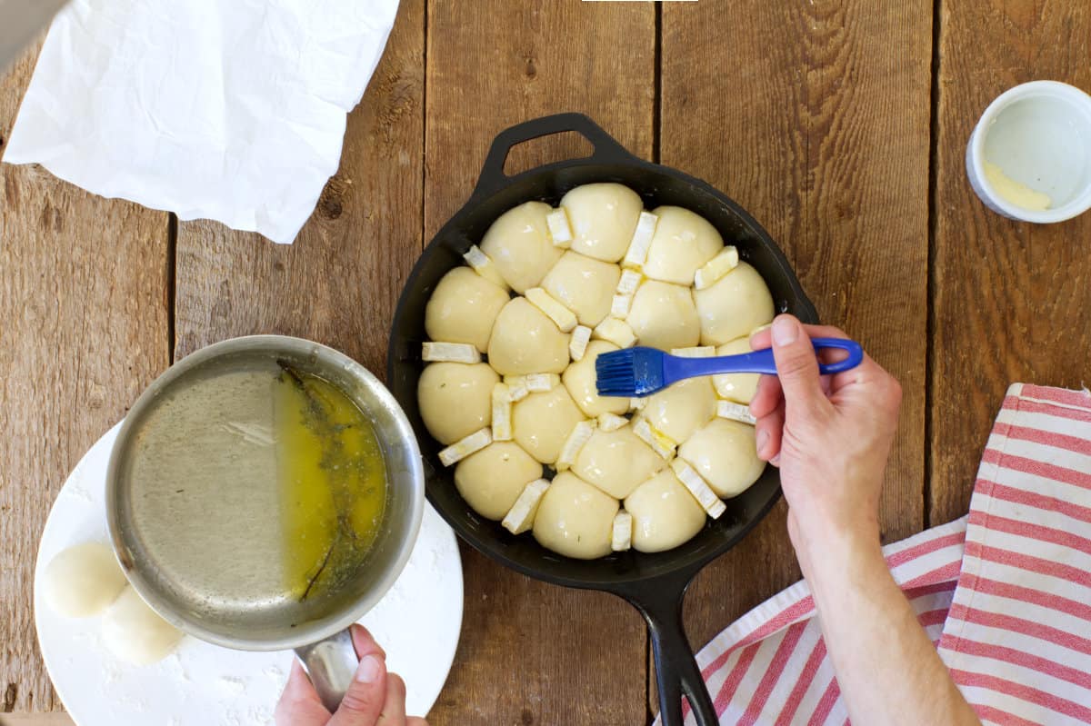 Proofed cranberry brie pull apart bread being brushed with butter prior to baking.