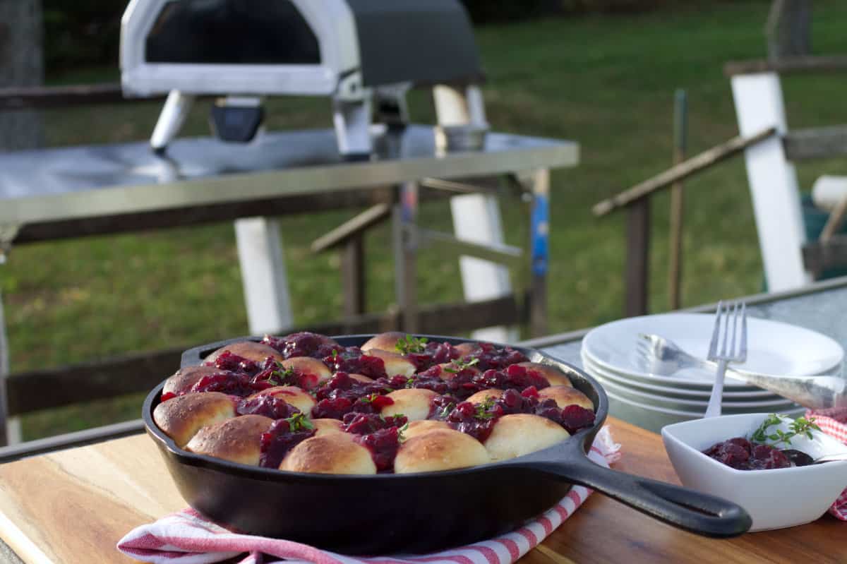 Cranberry brie pull apart bread in a cast iron skillet, displayed with an Ooni pizza oven in the background.