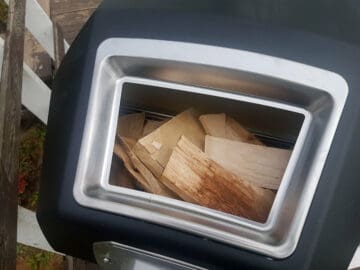 The back fuel compartment of an Ooni Karu 16 filled with firewood about to be lit.