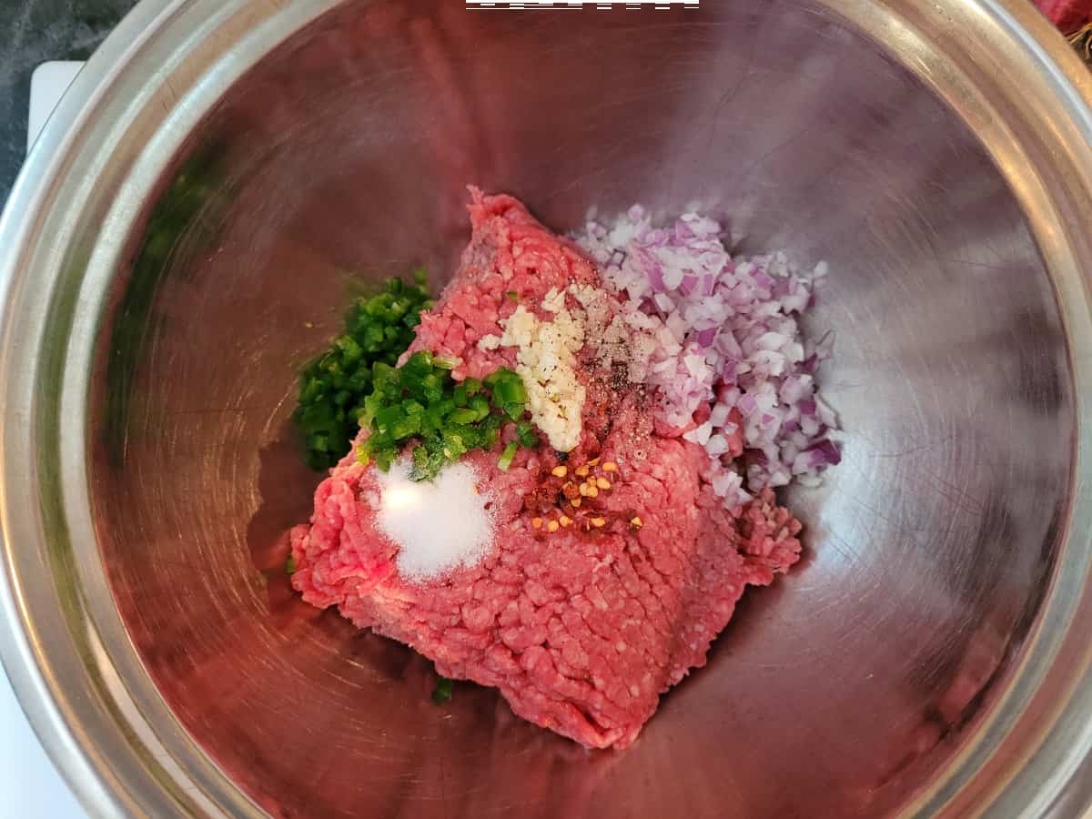 All the ingredients for meatballs in a stainless steel bowl. 