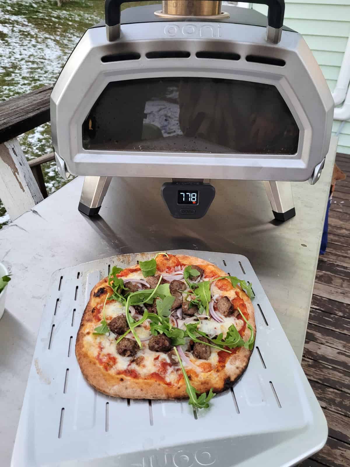Wood fired meatball pizza fresh out of the ooni pizza oven on a steel pizza peel.