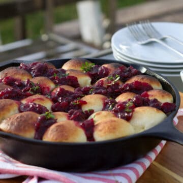 Close up image of cranberry brie pull apart bread in a cast iron skillen in an outdoor patio setting.