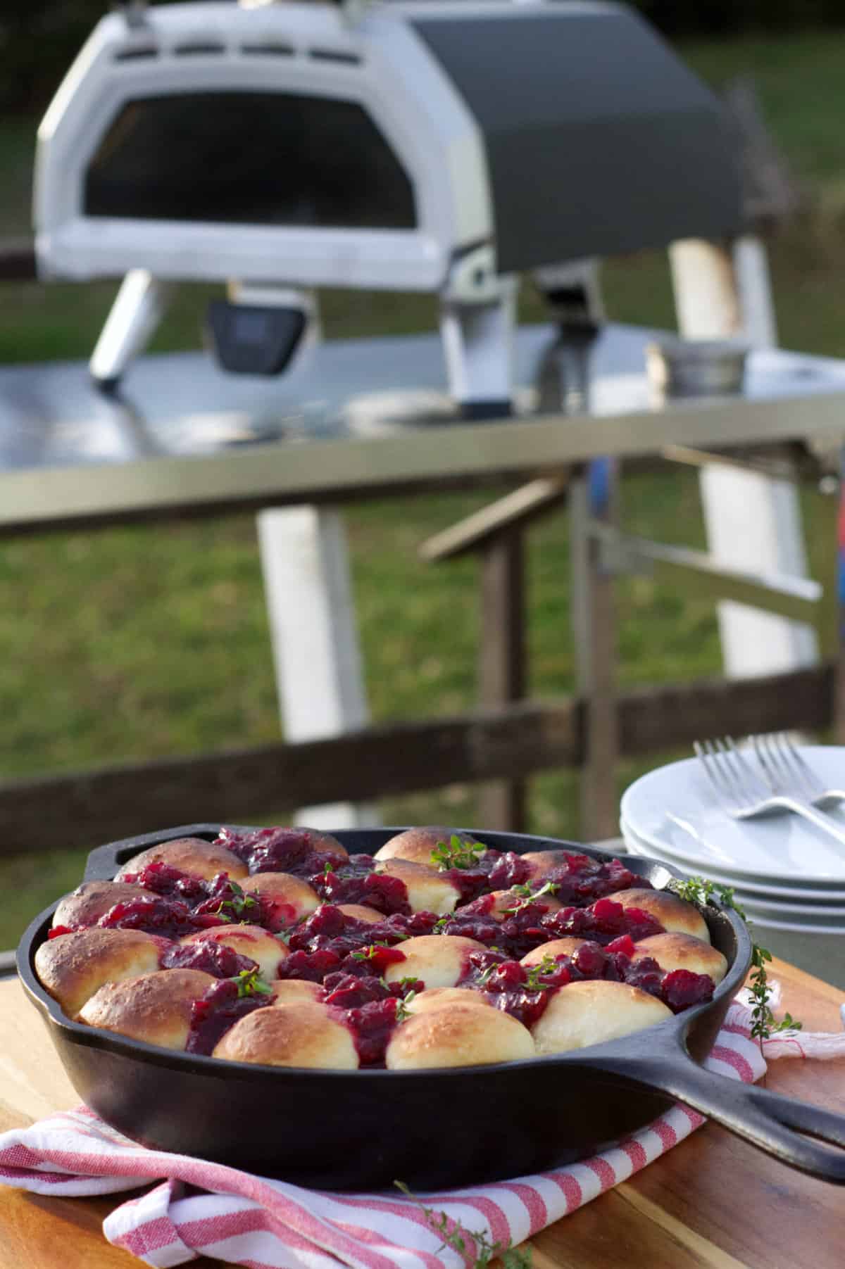 Cranberry brie pull apart bread in a cast iron skillet, displayed with an Ooni pizza oven in the background.