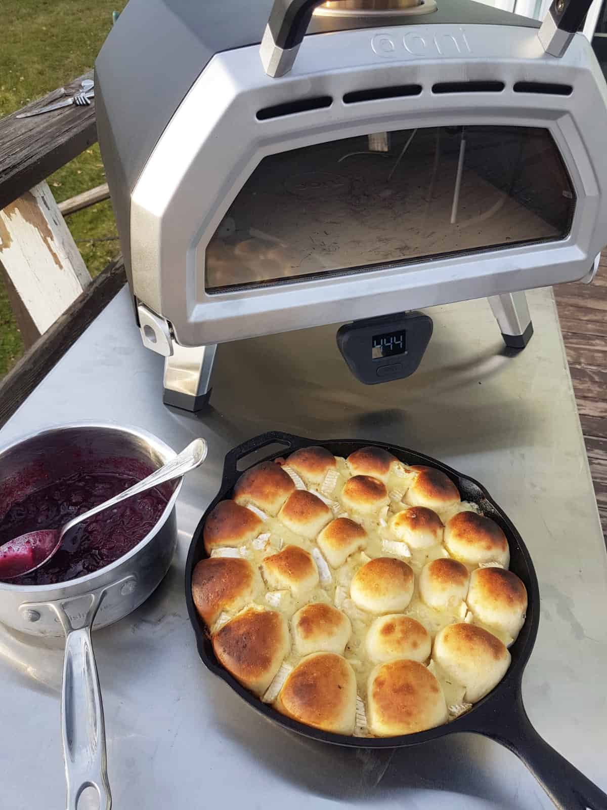Freshly baked cranberry brie pull apart bread, in front of a Ooni pizza oven.