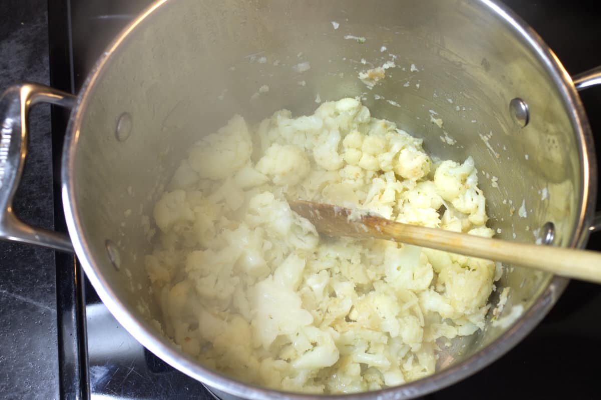 Cauliflower starting to break down as it cooks in a large soup pot.