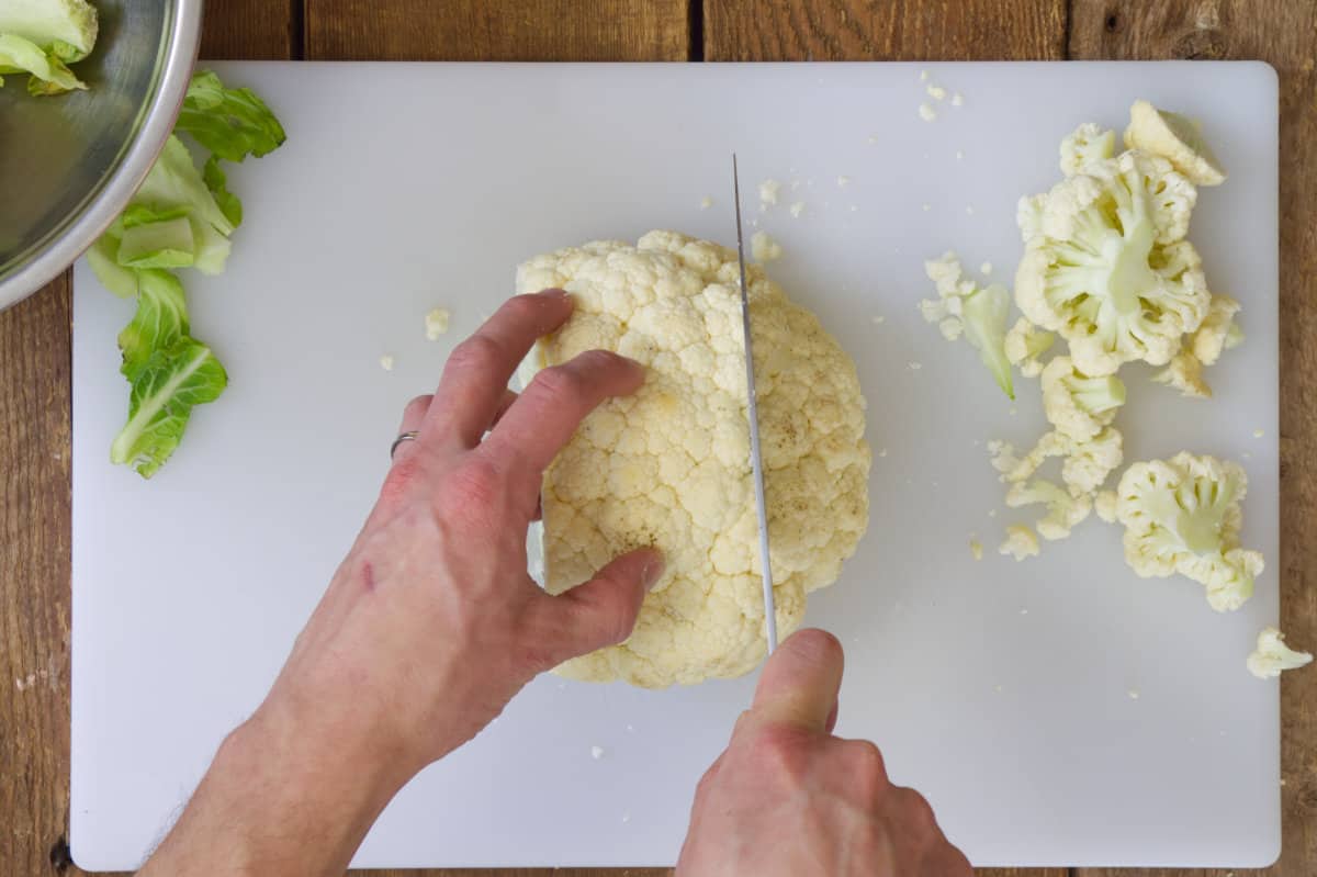 Overhead view of trimming a head of cauliflower in preperation of cutting cauliflower steaks.