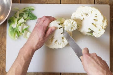 Overhead shot of cutting cauliflower florets away from the core.