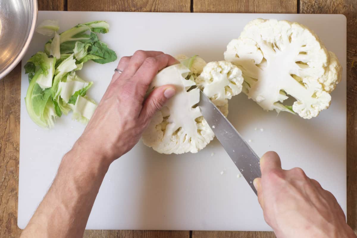 Overhead shot of cutting cauliflower florets away from the core. 