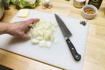 Roughly chopped spanish onion on a white cutting board.