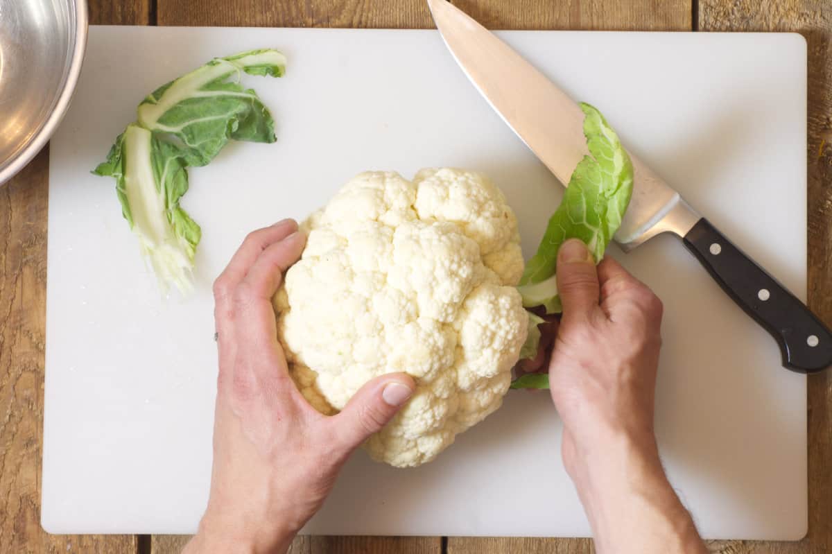 Removing cauliflower leaves from the cauliflower.