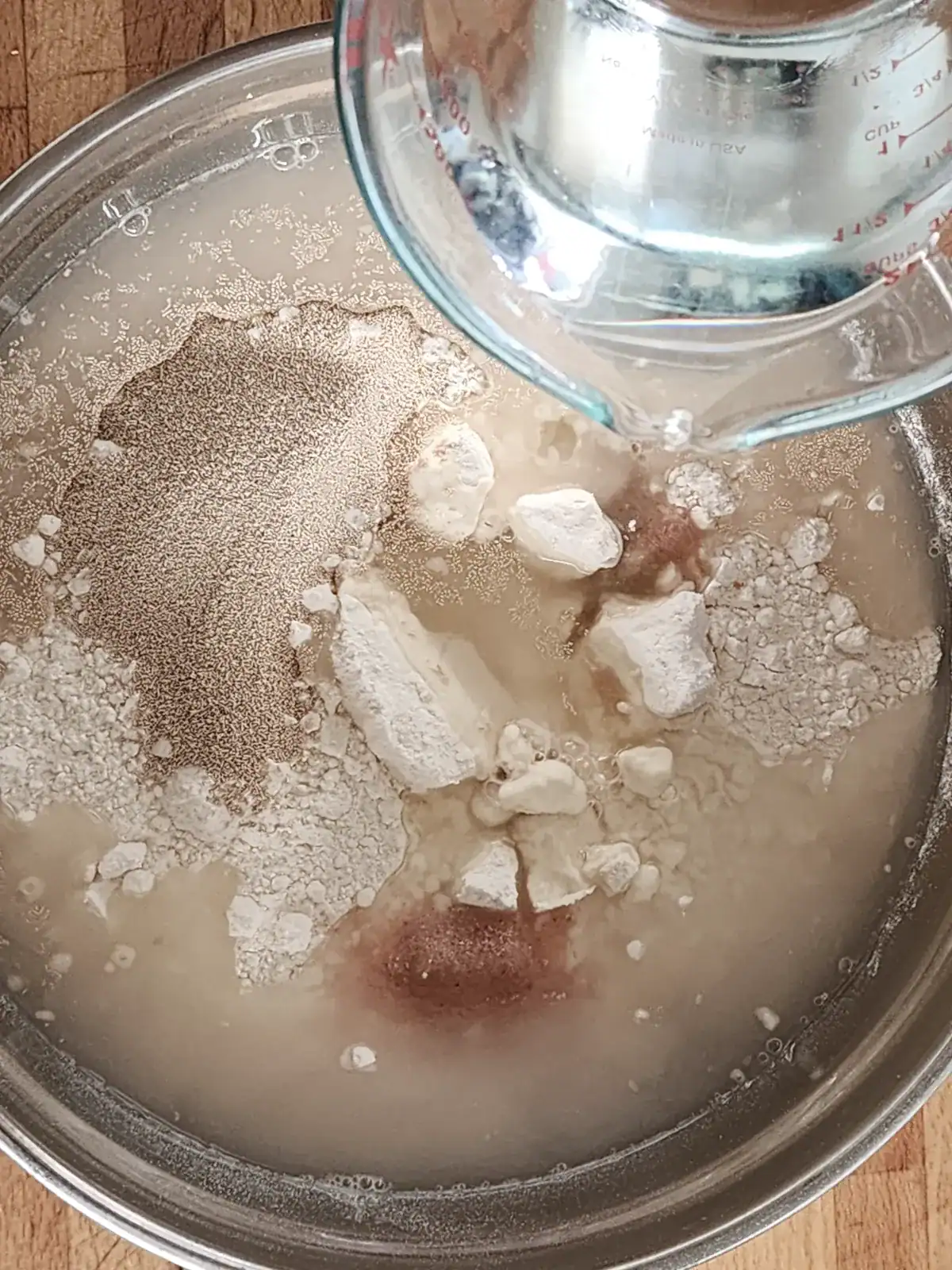 Homemade pizza dough ingredients - flour, salt, yeast, sugar and water - placed in the bowl